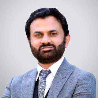 Professional headshot of a bearded man in a gray suit and paisley tie facing the camera.
